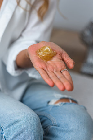 The hands of the beautician hold liquid sugar paste or wax for the duration of the depilation procedure in the salon. close up, background imageの写真素材
