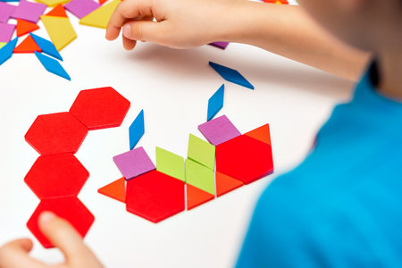 Close up of kid hands playing bright wooden tangram toy. The child collects a pattern of wooden bars. Creative baby make new forms.の写真素材