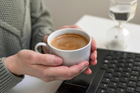Woman drinking coffee and using digital tablet, laptop. Sitting at the tableの写真素材