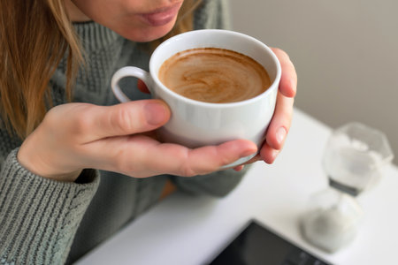 Woman drinking coffee and using digital tablet, laptop. Sitting at the table