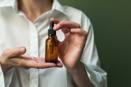 Essential oil with a pipette in the hands of a woman with space to copy. Women's hands with a bottle of oil and a pipette - the sphere of beautyの写真素材