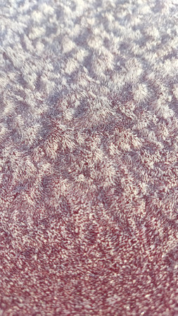 Textured background of blue ice on a smooth red surface in winter. Frost on a red background...