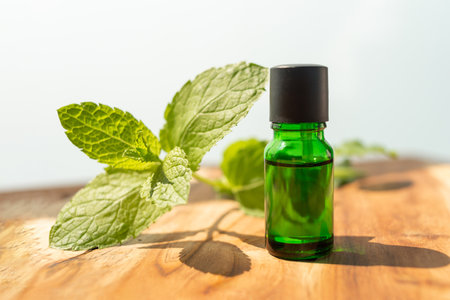 Green bottle of essential oils. natural cosmetics for skin care. A bottle and fresh mint on a wooden...