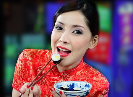 young asian woman eating sushi on a colored backgroundの写真素材