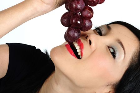 Beautiful young asian girl eating grapeの写真素材