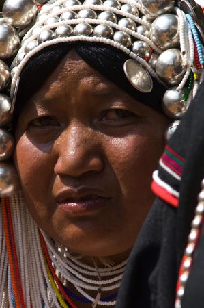 Thailand , portrait of a akha or kalo woman. This tribe live in the mountains of china, laos, myanmar and northern of thailand. The headdress made with rows of beads is embellished with silver globsの写真素材