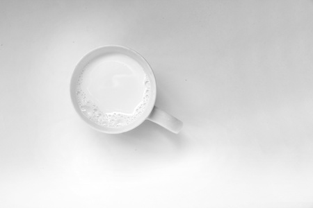 frothy milk in a cup on a light backgroundの写真素材