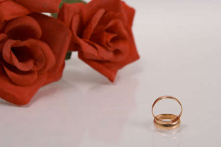 Two wedding rings and red rose at the backgroundの写真素材