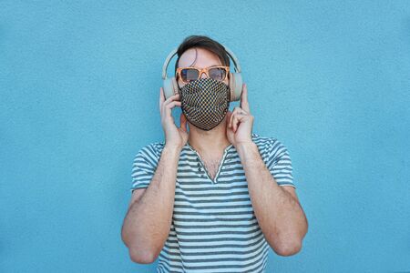 Boy with headphones on listening to music in covid-19 time with face mask and keeping the social distanceの写真素材