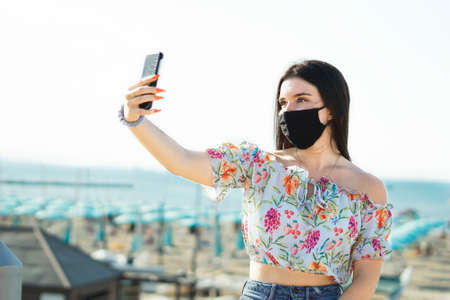 Portrait of a pretty girl taking a selfie with face mask in covid-19 time