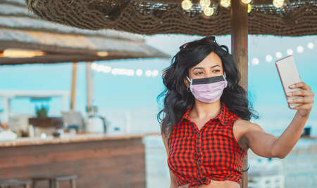 African american woman taking selfie with face mask onの写真素材
