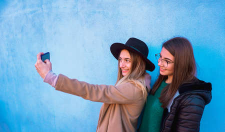 Teenagers taking selfie with smartphone with wall background - Girls using cellphone to take photo - Technology conceptの写真素材