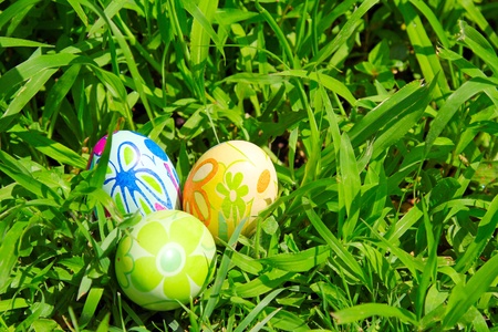 Three painted easter eggs on the green grass background