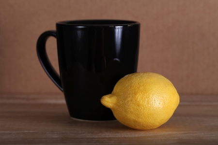 Yellow fresh whole lemon and black coffee mug and yellow lemon still life, shallow focusの写真素材