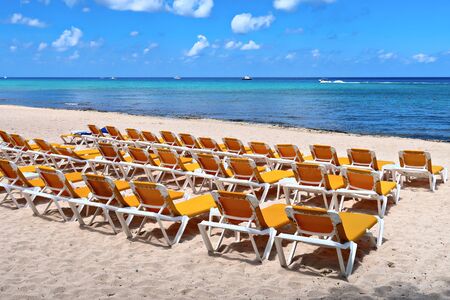Sunbeds on the tropical beach on the sand and sea background