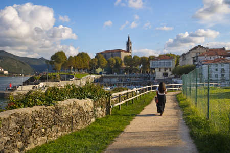Mundaka, Bizkaia; Oct. 09, 2021. The coastal town of Mundaka in the Urdaibai biosphere reserve. A woman walking along the new promenade to the fishing portのeditorial素材