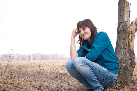 The girl sits at a tree and smiles.の写真素材