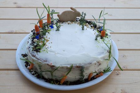 Carrot cake with mascarpone cream and honey rabbit on a wooden background