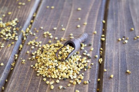 Bee pollen grains in wooden spoon on wooden table