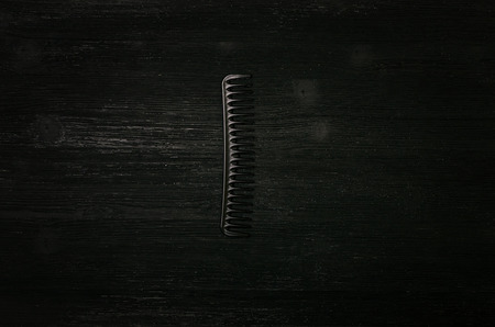 Black plastic hair comb isolated on black wooden background. の写真素材