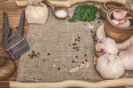 Garlic bulb and cloves, pepper peas, salt, greenery dill on the brown wooden table background. Different Spices. Ingredients for marinade.の写真素材