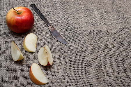 Sliced apple with vintage knife on burlap cloth background with copy space. Fruit compote ingredient.の写真素材