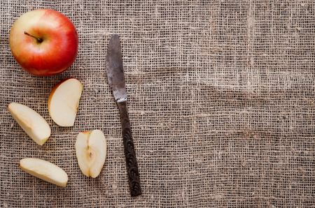 Sliced apple with vintage knife on burlap cloth background with copy space. Fruit compote ingredient.の写真素材