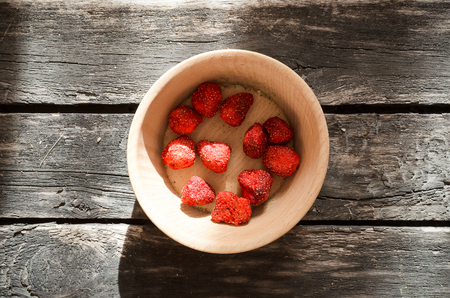 Freeze dried strawberry in the wooden bowl on timber plank background.の写真素材