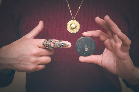 Astrologer demonstrates in his hand a Zodiac talisman plate and showing on it by his index finger. Horoscope wheel. Astrology concept.の写真素材