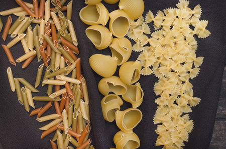 Pasta macaroni concept background. Scattered on the kitchen table different sorts of pasta.の写真素材
