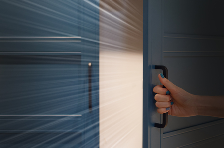 Women hand open door with mystic light behind. Unraveling of secrets concept.の写真素材