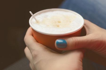 Hot coffee cappuccino in paper cup in female hands. Coffee break.の写真素材