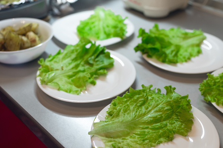 Green lettuce leaves on the plates on the kitchen table background.の写真素材