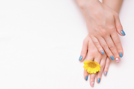 Woman hands with manicure on nails and yellow flower.の写真素材