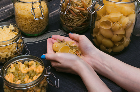 Different kinds of pasta in female hands.の写真素材