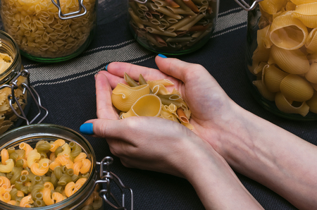 Different kinds of pasta in female hands.の写真素材