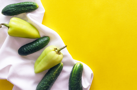 Cucumber and bell pepper with kitchen towel on yellow background with copy space.の写真素材
