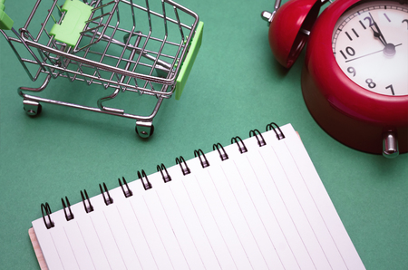 Shopping cart, red alarm clock and shopping list isolated on color background. Time to shop.の写真素材