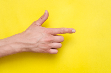 Male hand pointing by index finger isolated on yellow background.