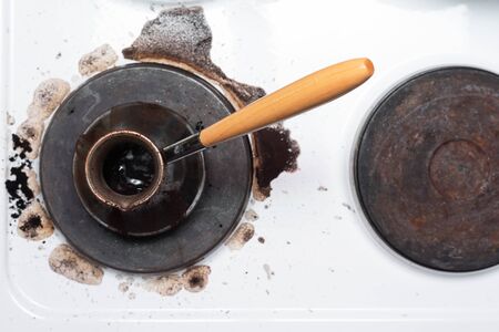 Spilled coffee from the Turk on the stove abstract background.の写真素材