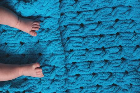 Legs of a newborn baby on a blue soft bedspread with copy space .の写真素材