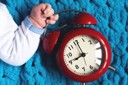 Baby hand with a red alarm clock. Time to eat.の写真素材