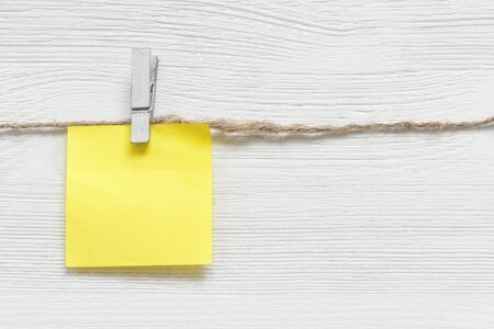 Blank paper stickers with copy space on a clothespin on a rope on a white table background. To do list template.の写真素材