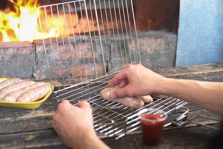 Raw barbecue sausages on a grill grate on a kitchen table background.