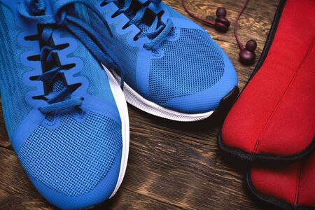 Sneakers, ankle weights and a headphones on a brown floor. Sport background.の写真素材