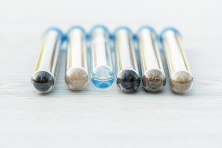 Samples of different types of soil in test tube on the table. Soil science concept.