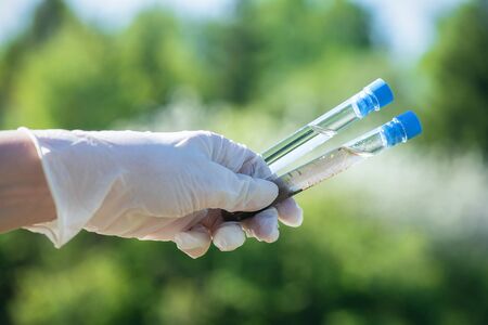 Scientist is holding in hands a clear and dirty water test tubes close up.の写真素材