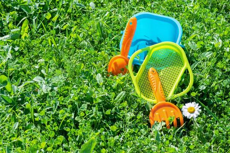 Baby toys a shovel and bucket on green meadow background with copy space.の写真素材