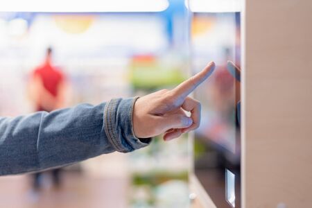 Woman is choosing a goods in an interactive information stand in the store.の写真素材