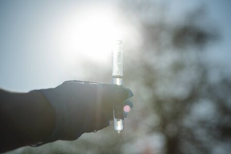 Pond water pollution concept. Scientist takes samples of dirty water from a pond into a test tube.の写真素材